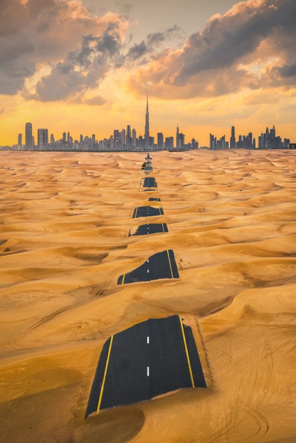 Aerial view of Dubai Downtown skyline with half desert sand road, United Arab Emirates or UAE. Financial district and business area in smart urban city. Skyscraper and high-rise buildings at sunset.